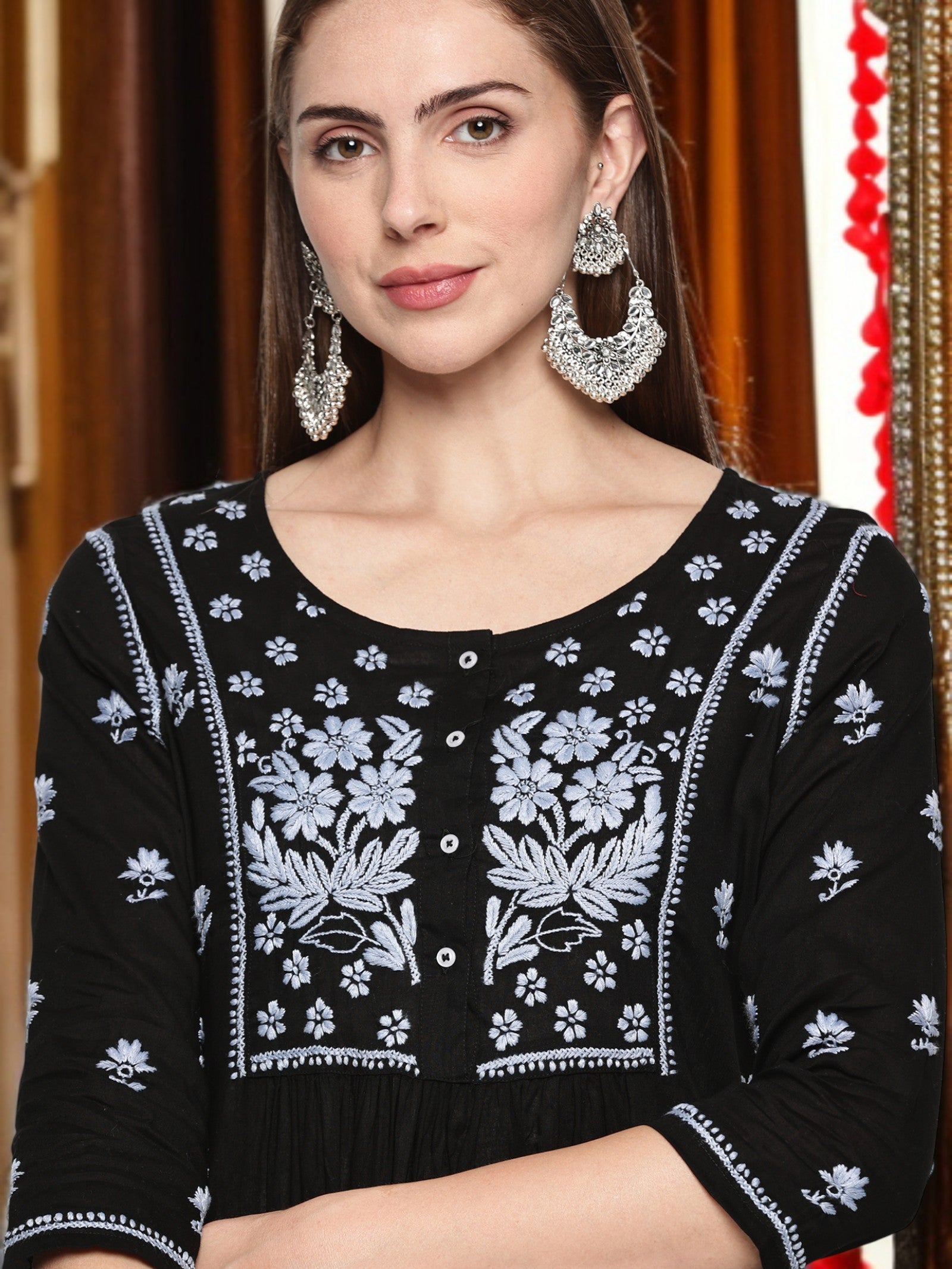 Woman wearing a black kurta  with floral embroidery against a blurred background