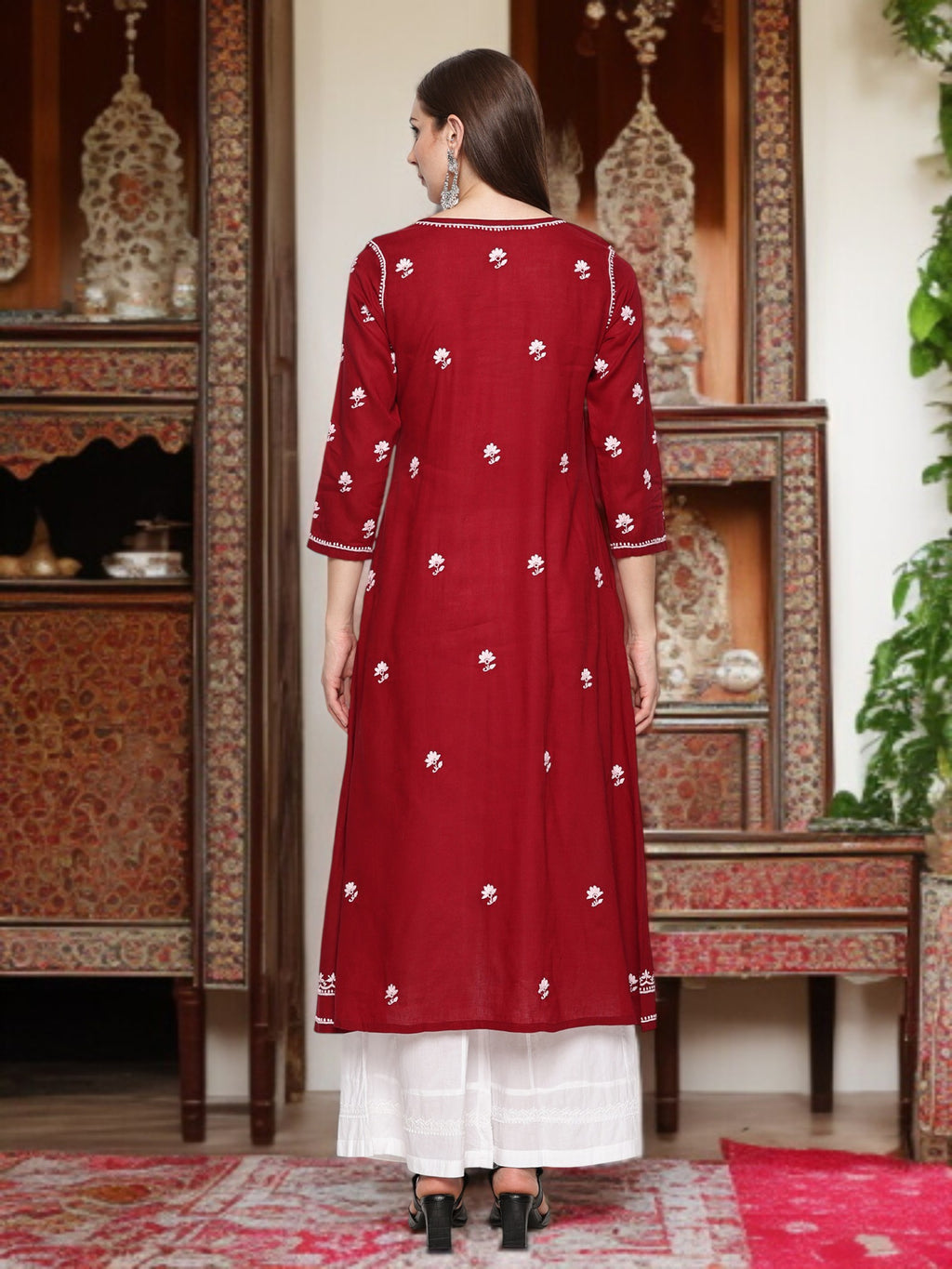 A woman wearing a maroon and traditional outfit in an ornate room.