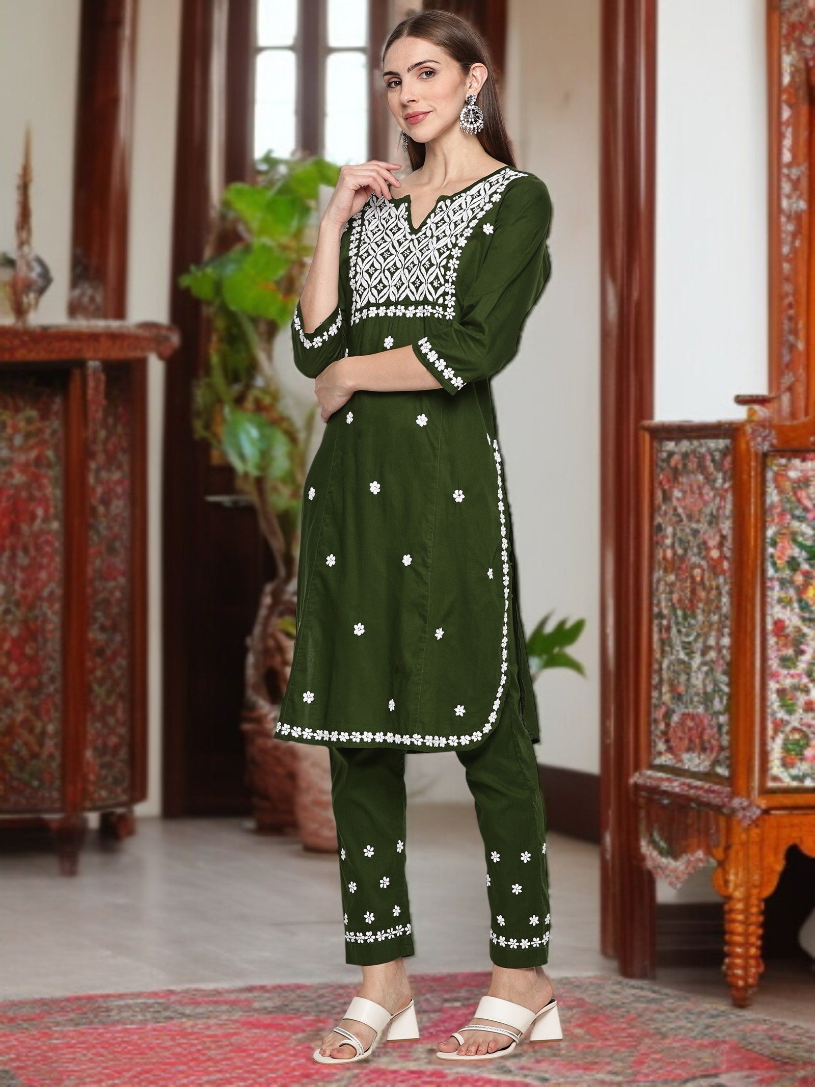 A woman wearing a traditional outfit with intricate patterns in a decorated room. mehndi