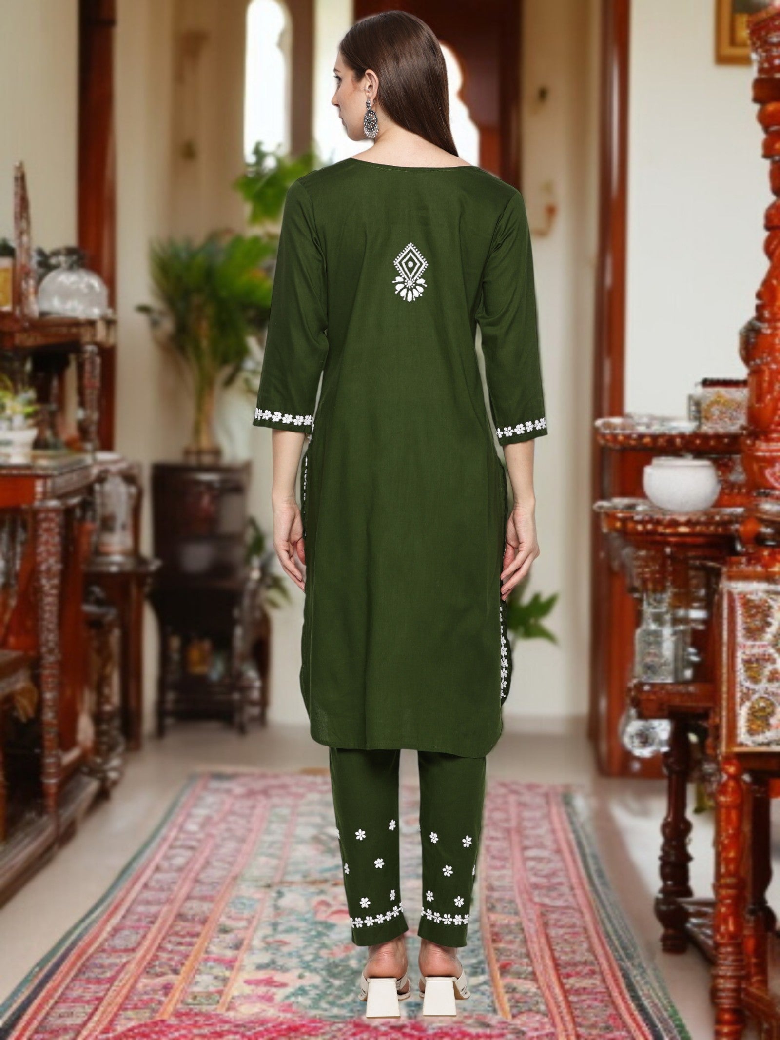 A woman wearing a traditional outfit with embroidery in a decorated room. mehndi