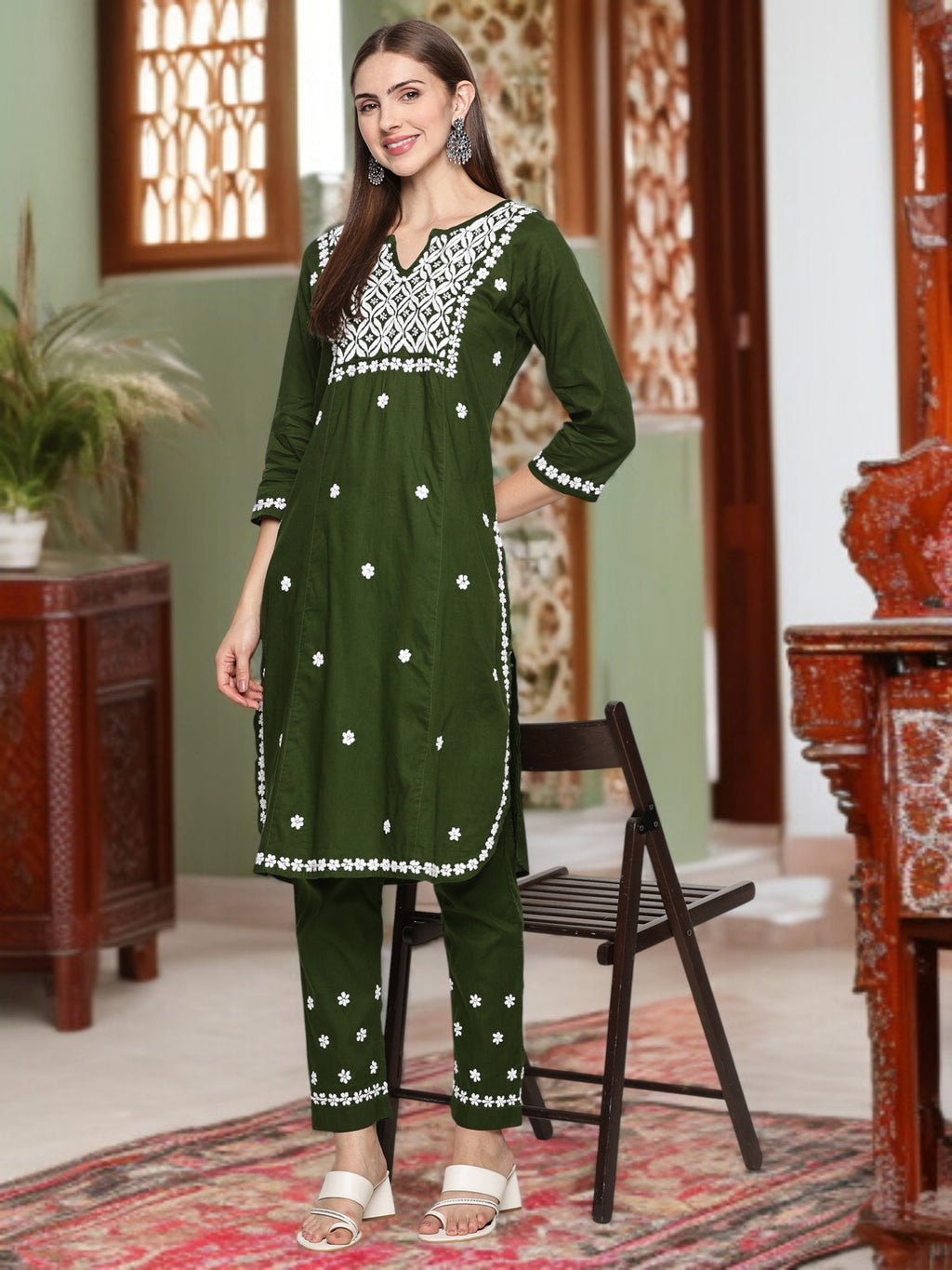 A woman wearing a green embroidered outfit in an indoor setting.mehndi