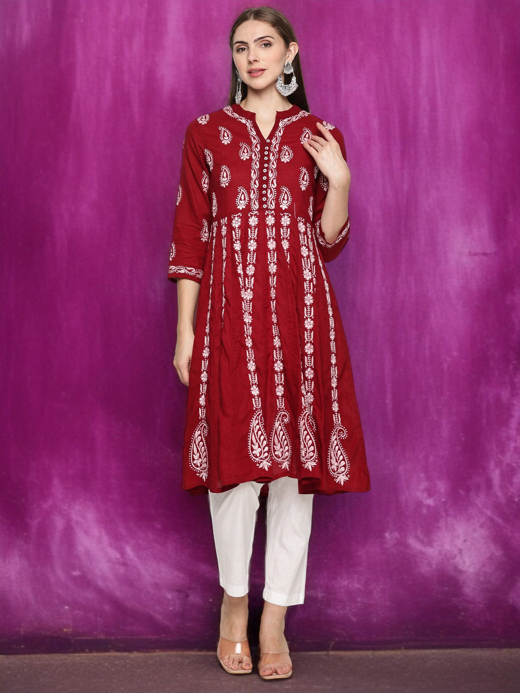 Woman wearing a maroon embroidered kurta with pants against a purple background