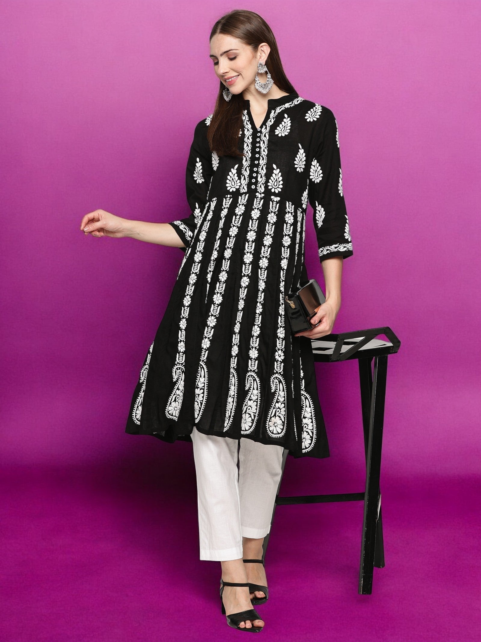 Woman wearing a black and patterned kurta with pants against a purple background