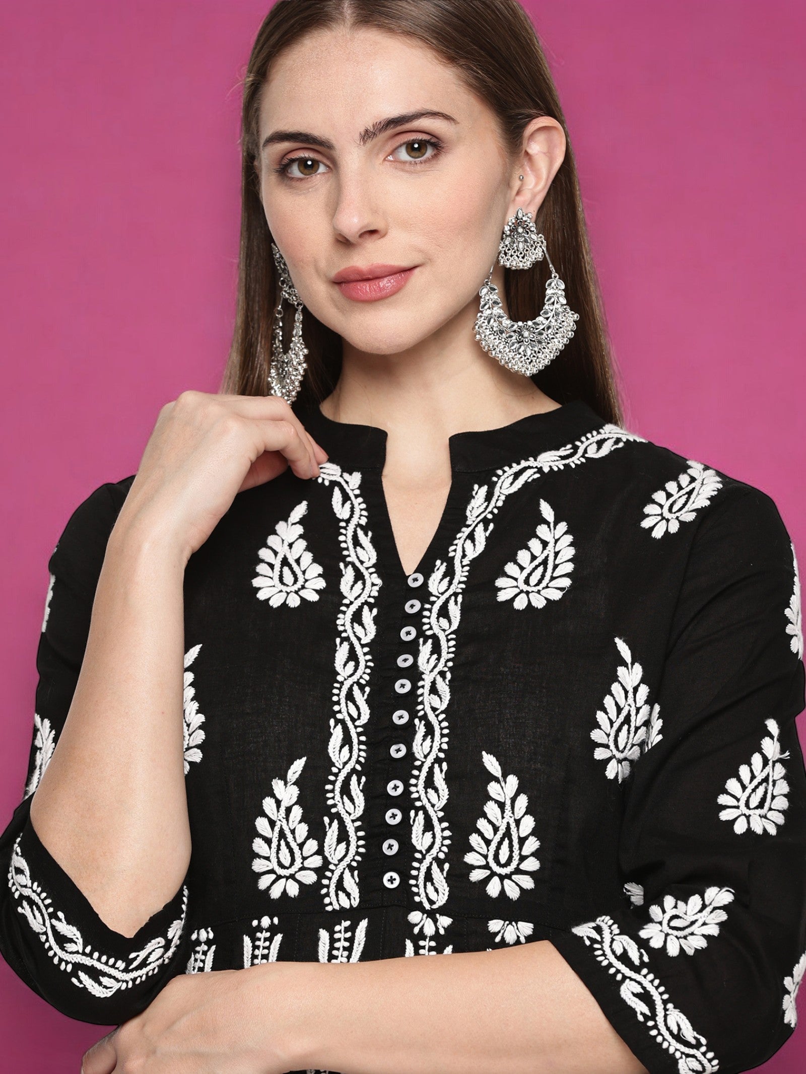 A woman wearing a black embroidered Kurta with silver earrings 