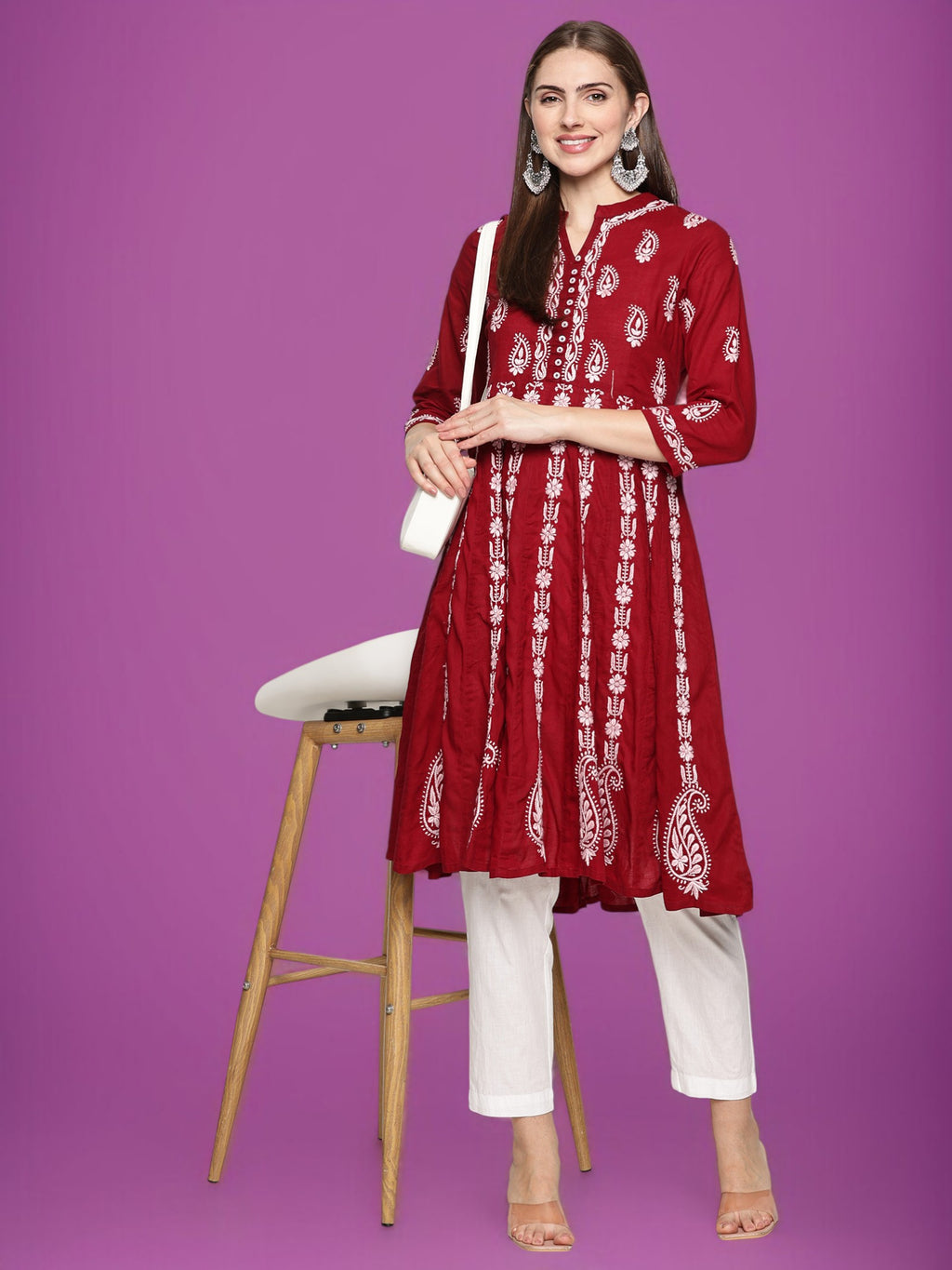 Woman wearing a maroon and  patterned kurta with  pants on a purple background