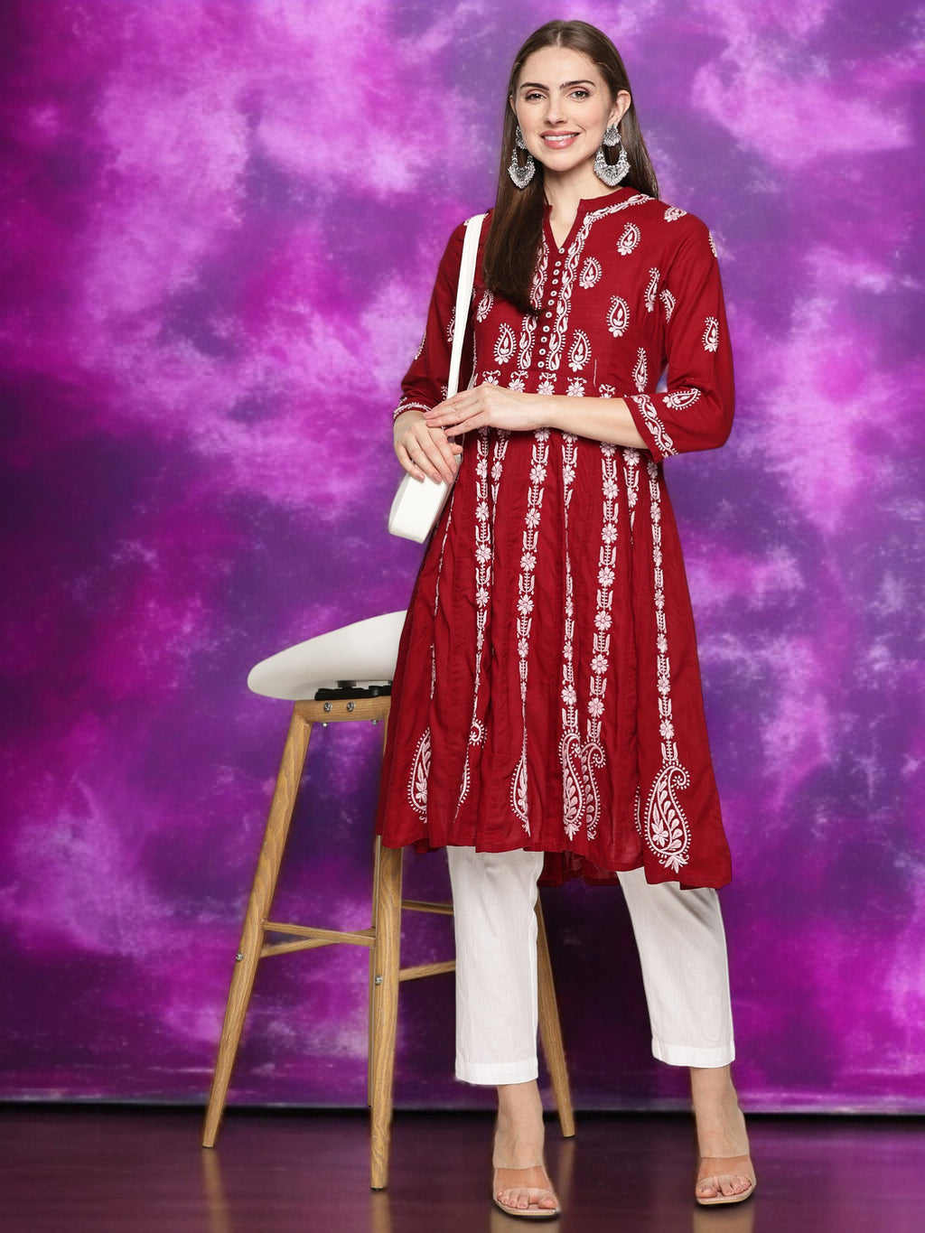 Woman wearing a maroon embroidered kurta with pants against a purple background
