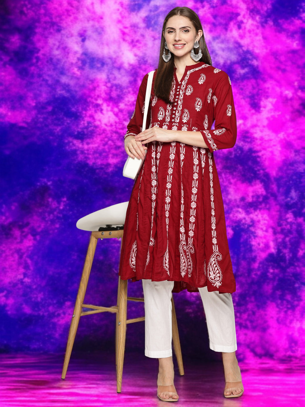 Woman in a maroon embroidered kurta with pants against a vibrant purple background