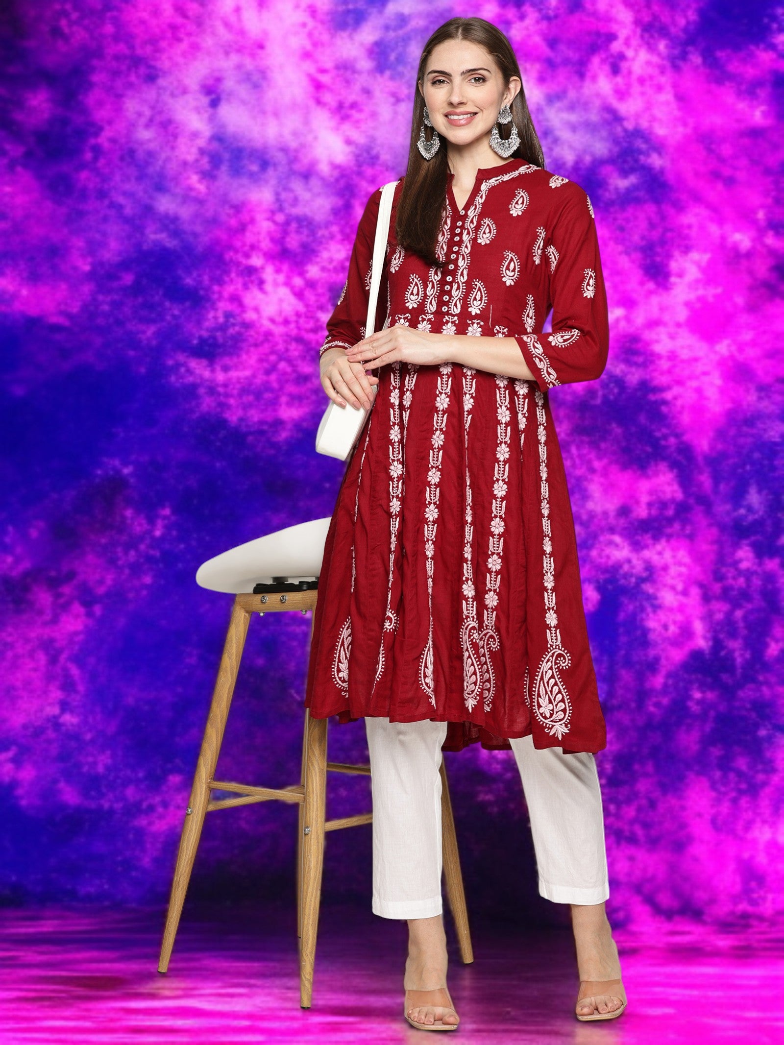 Woman in a maroon embroidered kurta with pants against a vibrant purple background