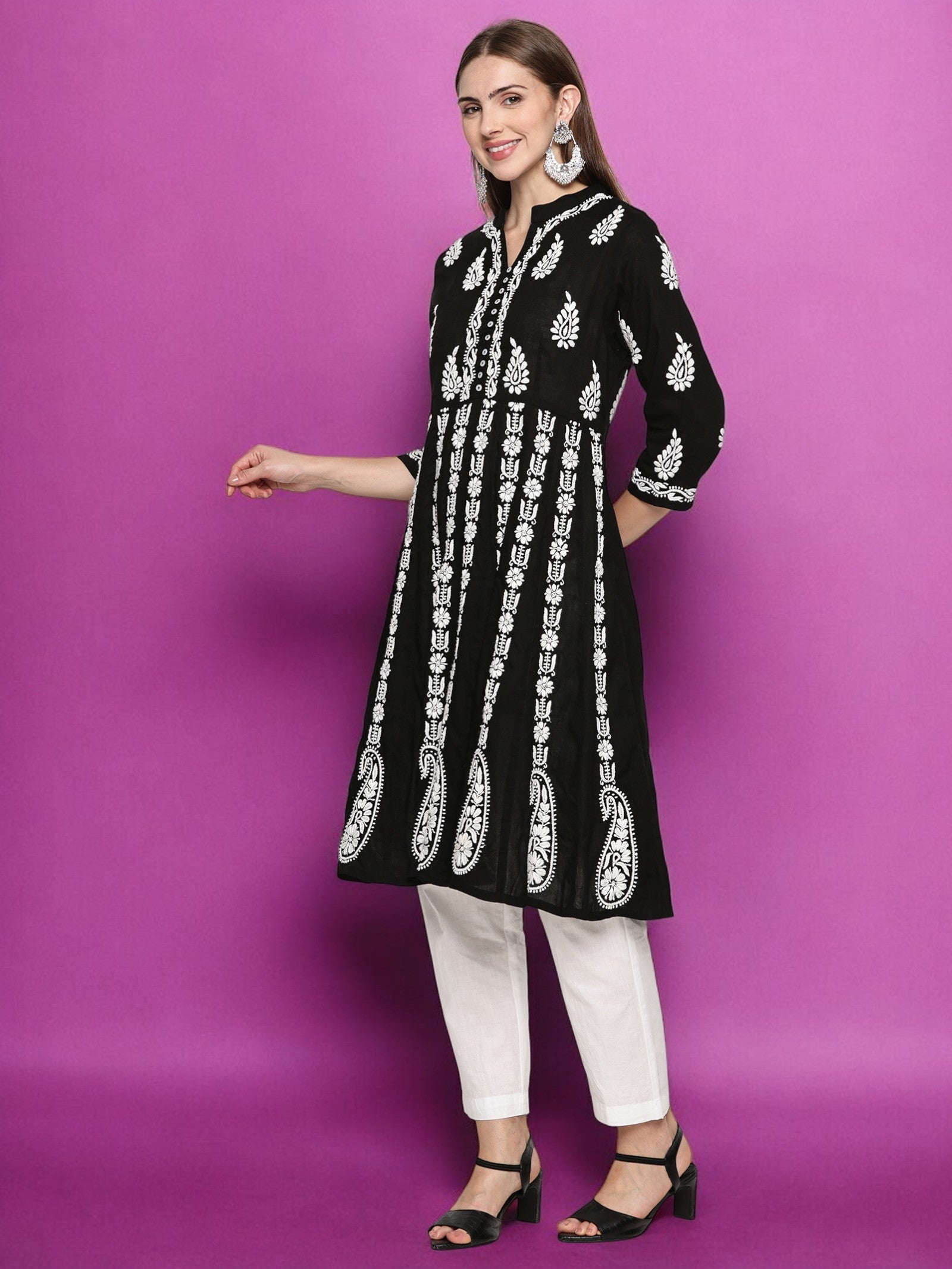Woman wearing a black and patterned kurta with  pants against a purple background