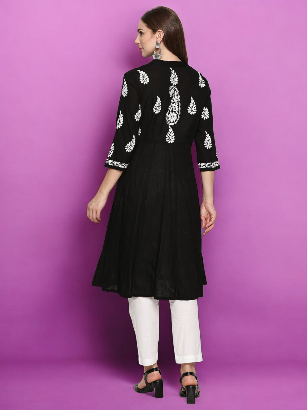 A woman wearing a black kurta with embroidery on a purple background