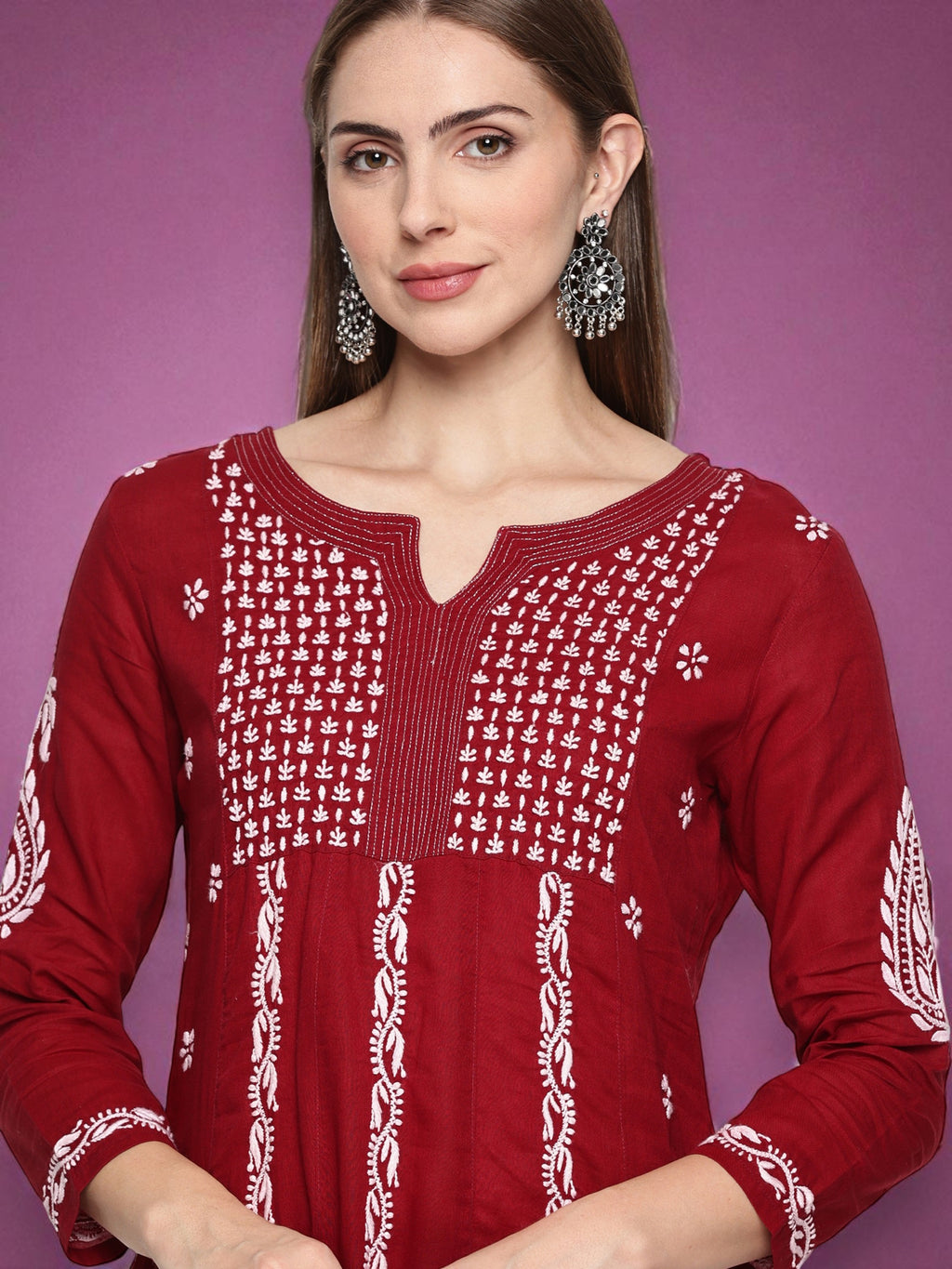 Woman wearing a red embroidered top against a purple background