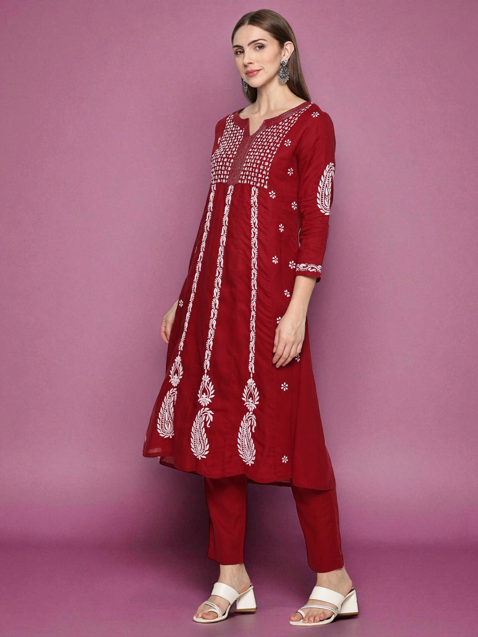 Woman wearing a red embroidered outfit against a pink background